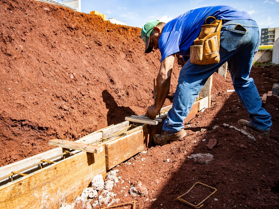Worker setting wood forms and rebar for a foundation footing