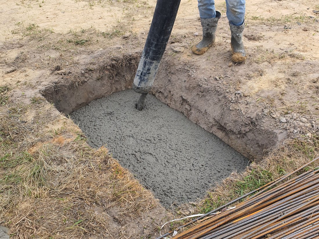 Concrete being poured into a foundation footing with rebar nearby