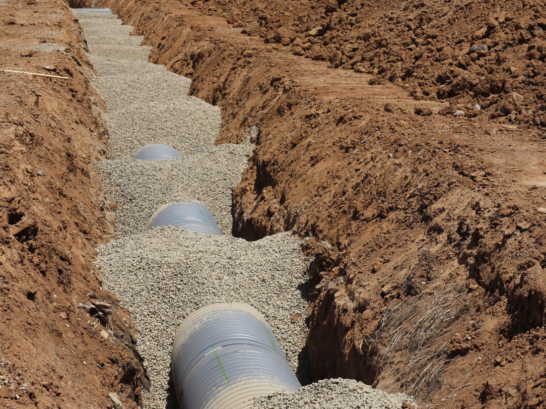 Pipe bedded in gravel inside an excavated trench