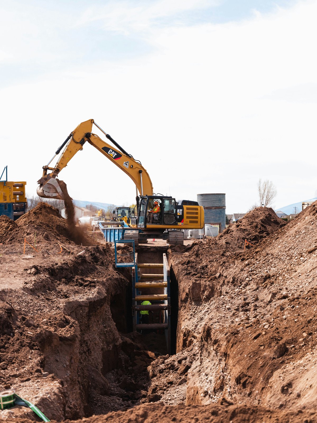 Excavator digging a deep trench at a construction site