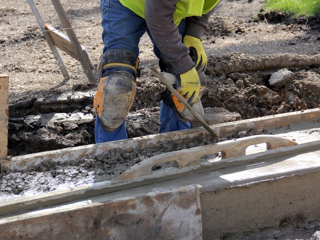Worker finishing a concrete curb with a hand tool